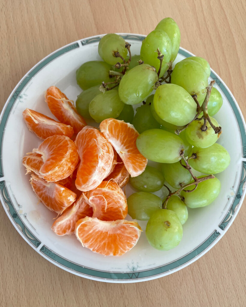 Teller mit Mandarinen und Weintrauben