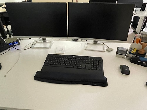 Schreibtisch mit zwei Bildschirmen und Tastatur