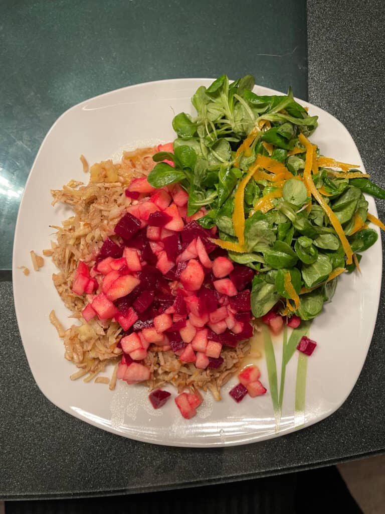 Teller mit rote Beeten, Apelstücke, Schwarwurzel und Rucolasalat