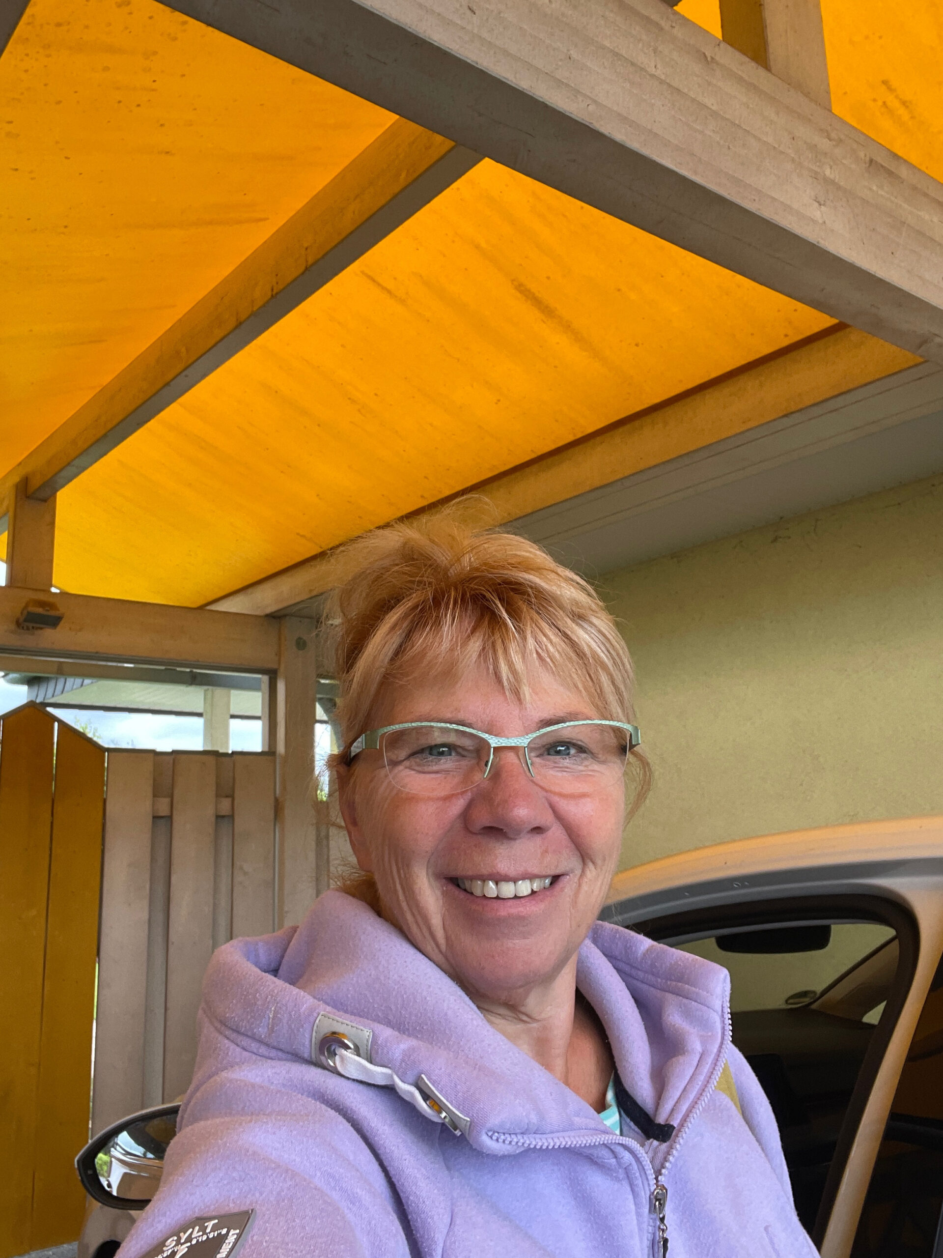 IMG_2024-09-13-181616 Frau in einer Jacke Farbe Lila vor einem weißen Auto